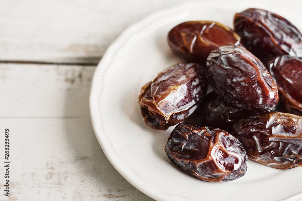 Fototapeta premium Dried dates on white plate. Healthy snack. Traditional dessert during Ramadan month