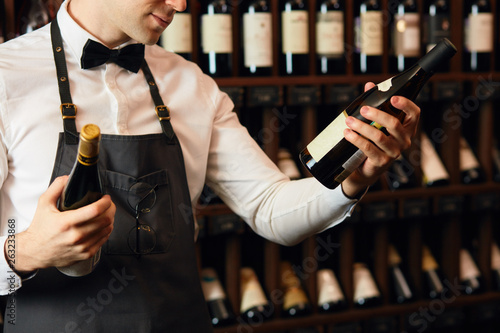 Fotografía Elegant wine seller holding a bottle of wine and reading label in a wine store