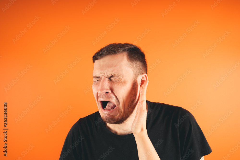 Man getting slapped on orange background Unhappy scared man getting slapped standing on orange background