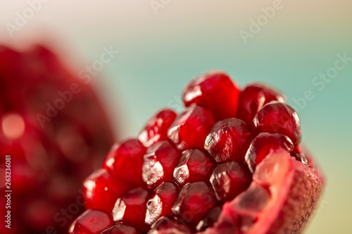 Slice of a juicy pomegranate with grains of closeup. Beautiful blurry backdrop and red seeds pomegranate. Macro image of fruit. Soft focus. Copy space. Healthy concept.
