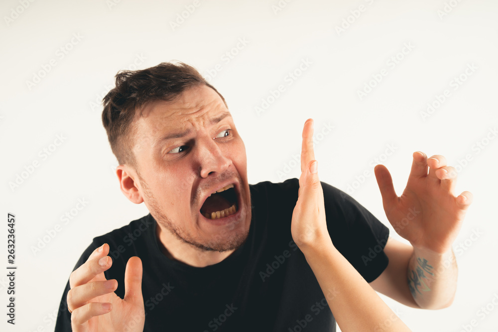 Emotional male getting slapped in face while shouting with closed eyes in fear on white background Emotional male getting slapped in face while shouting with closed eyes in fear on white background