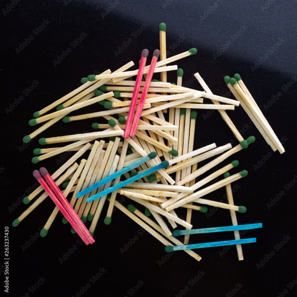 homosexuality concept: several pairs of blue and pink matches in front of a pile of ordinary matches, black background, short focus, limited lighting, toning