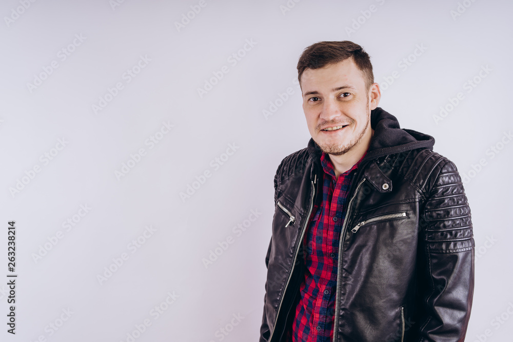 Man in trendy jacket on white background. Portrait of young male in leather jacket zipping up and smiling at camera on white background Man in trendy jacket on white background. Portrait of young male in leather jacket zipping up and smiling at camera on white background