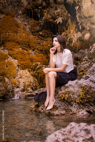 Beautiful girl posing in river  fairy fast forest in autumn.  Beauty  fashion. Spa  healthcare. Tropical vacation. Natural pool.