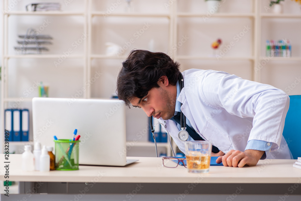 Young male doctor drinking in the office Young male doctor drinking in the office