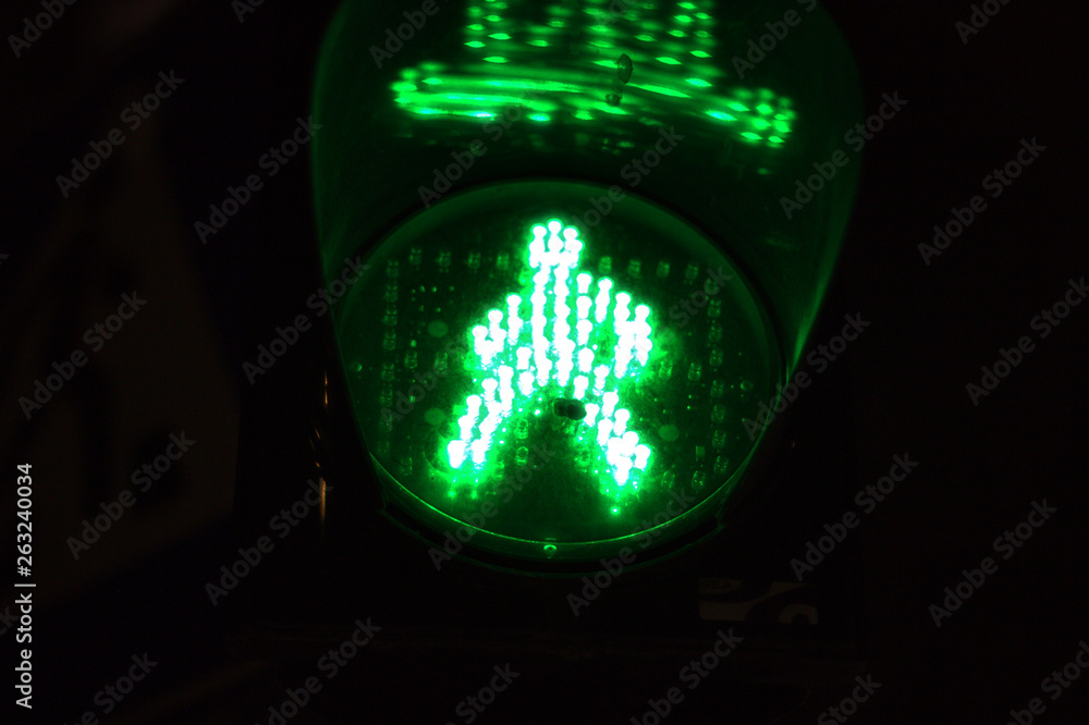 Green light of traffic light on the pedestrian crossing in the form of a human silhouette. Road crossing permit, signal to go for a pedestrian Green light of traffic light on the pedestrian crossing in the form of a human silhouette. Road crossing permit, signal to go for a pedestrian