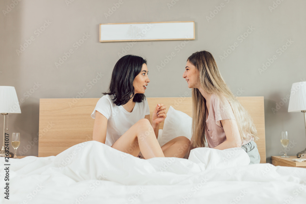 pleasant funny women having a chat while sitting on the comfortable bed. close up side view photo.whishful thinking pleasant funny women having a chat while sitting on the comfortable bed. close up side view photo.whishful thinking
