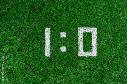 Football score 1:0.White numbers one and zero are drawn on the green grass