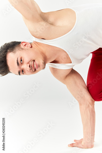 Free style dancer in red sports trousers doing some acrobatic stunts dancing break dance isolated over white studio background