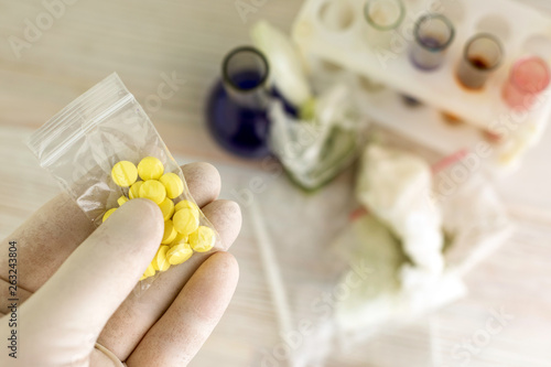 Quadro su tela study of synthetic drugs: a scientist holds a sample of a new drug above the tab