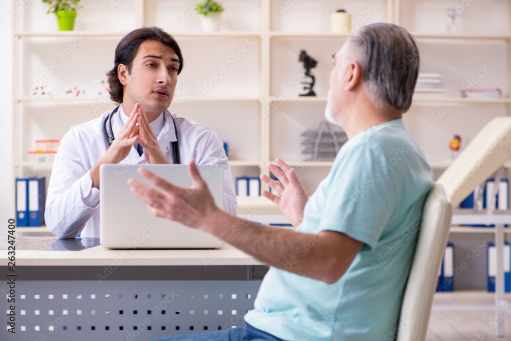 Old man visiting young male doctor Old man visiting young male doctor