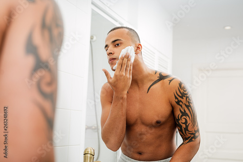 Reflection of man applying shaving foam in bathroom