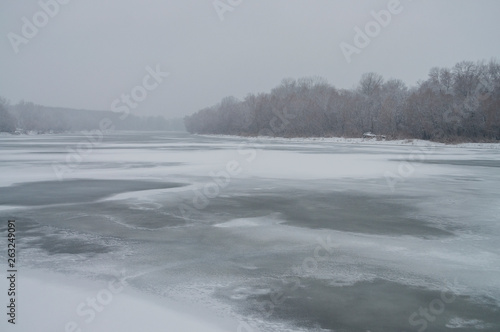 Winter day. River frozen - covered with ice and naked trees covered with white snow on there branches. Walking on nature