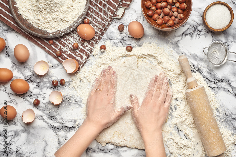 Close-up shot. Top view of a baker cook place, hands are working with a raw dough on the marble table background. Close-up shot. Top view of a baker cook place, hands are working with a raw dough on the marble table background.