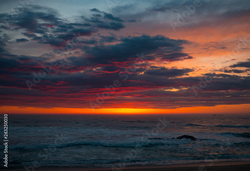 Dramatic red sunset sky with dark clouds over the ocean