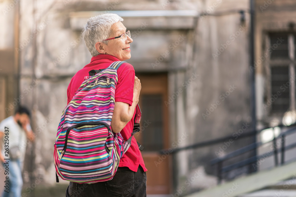 Senior old woman tourist with a backpack preparing to leave her home to go travelling Senior old woman tourist with a backpack preparing to leave her home to go travelling
