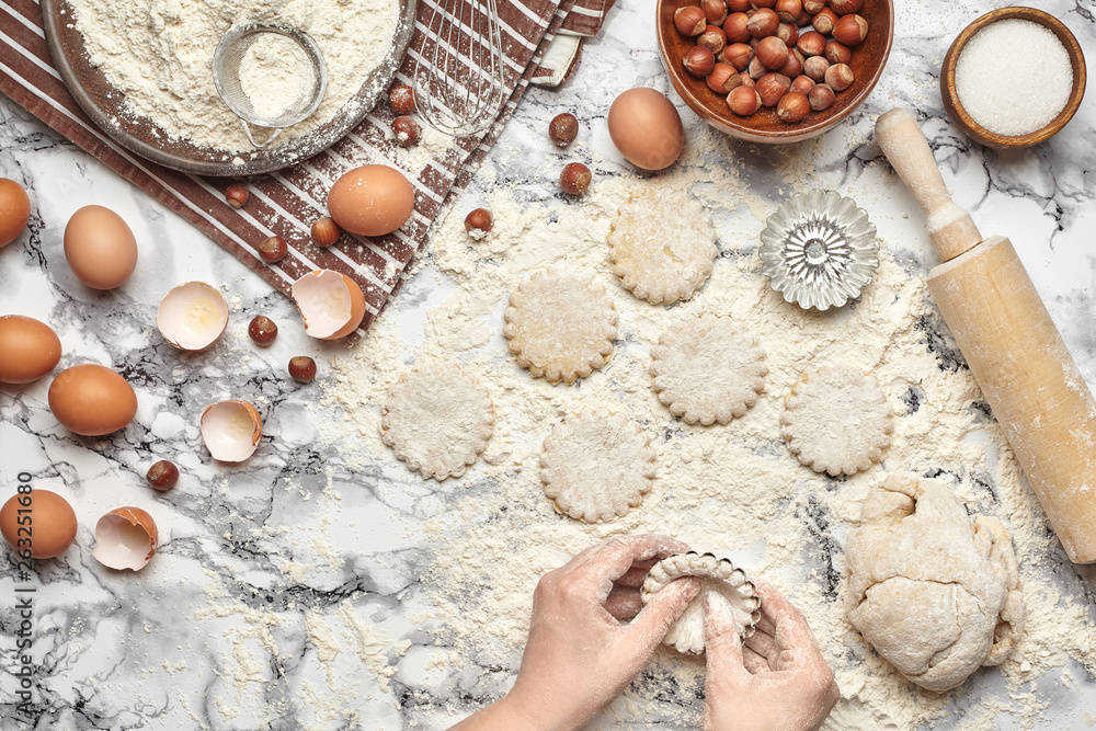 Close-up shot. Top view of a baker cook place, hands are working with a raw dough on the marble table background. Close-up shot. Top view of a baker cook place, hands are working with a raw dough on the marble table background.