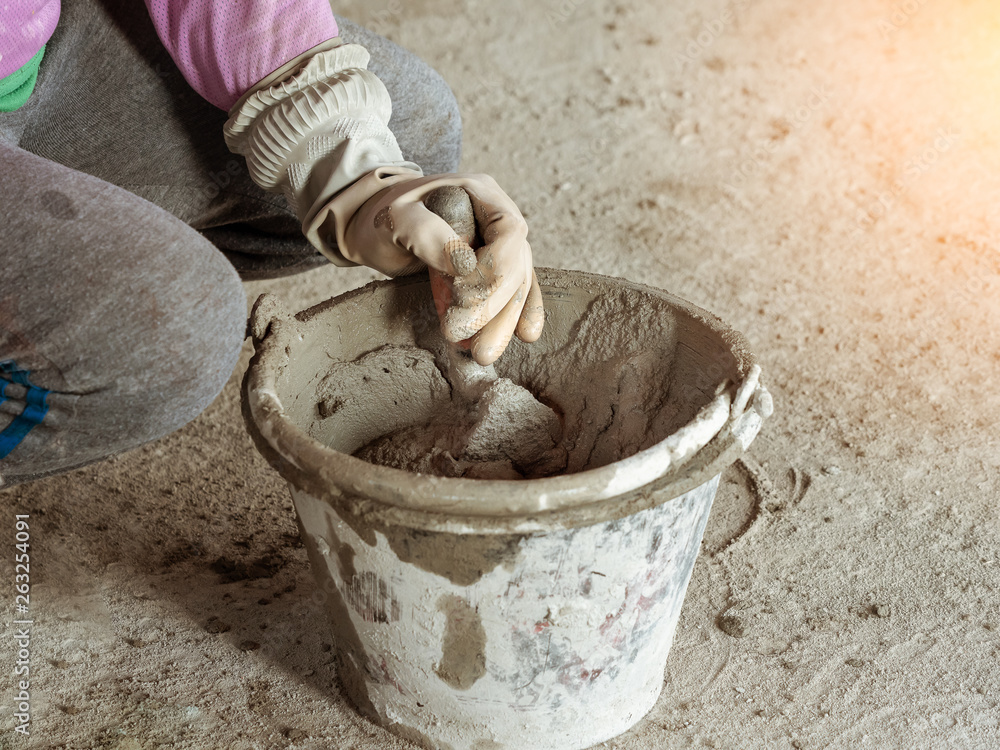 hand with trowel and bucket with mortar at consturction site hand with trowel and bucket with mortar at consturction site