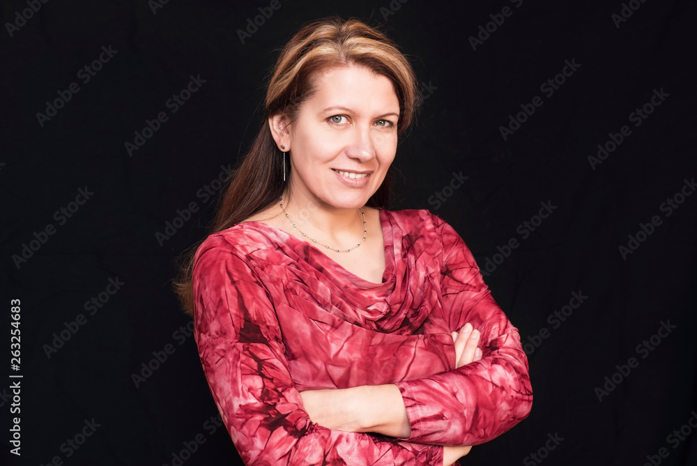 An awesome middle-aged woman smiles on a dark background. A woman is happy because she has a good family An awesome middle-aged woman smiles on a dark background. A woman is happy because she has a good family