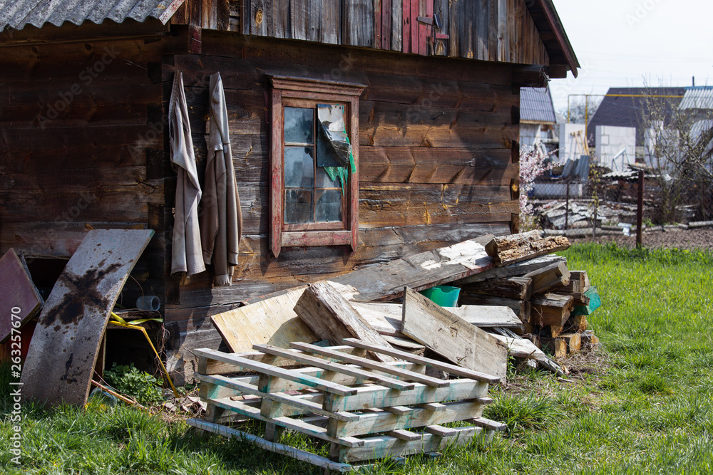 Old wooden rural house with construction waste in the yard Old wooden rural house with construction waste in the yard