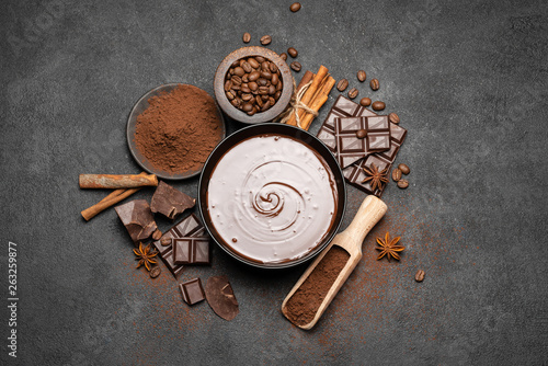 ceramic bowl of chocolate cream or melted chocolate and pieces of chocolate isolated on dark concrete background