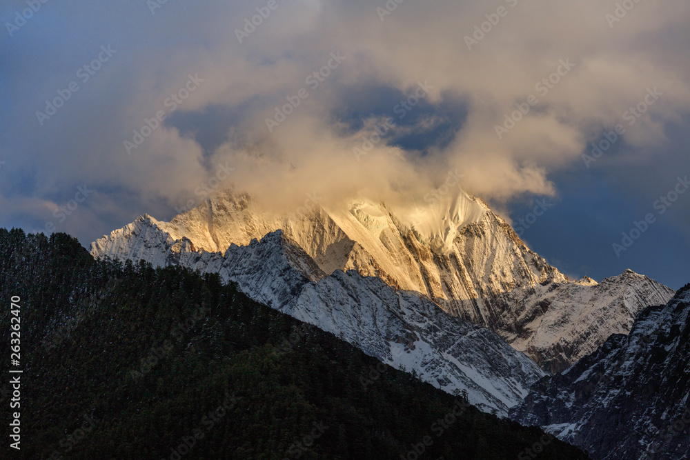 Obraz premium Chenadorje, holy snow mountain in Daocheng Yading Nature Reserve - Garze, Kham Tibetan Pilgrimage region of Sichuan Province China. Cliffs, Glaciers, Ice and Snow Mountain Summit View. Glowing Sunset