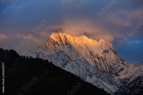 Chenadorje, holy snow mountain in Daocheng Yading Nature Reserve - Garze, Kham Tibetan Pilgrimage region of Sichuan Province China. Cliffs, Glaciers, Ice and Snow Mountain Summit View. Glowing Sunset