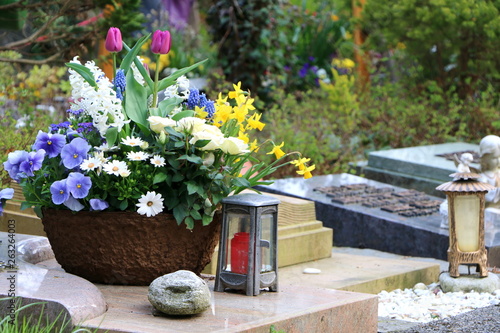 Obraz na płótnie Am Friedhof, Grabpflege, ein frühlingshaft bepflanzter Blumentopf und zwei Grablaternen w salonie