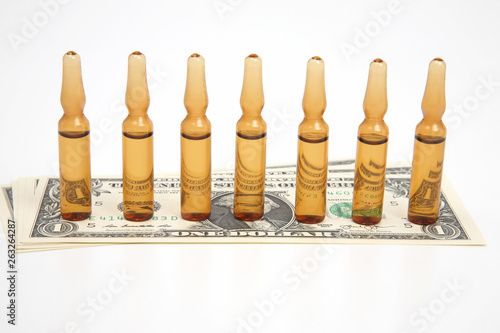 seven medical glass ampoules for injection on the background of dollar banknotes