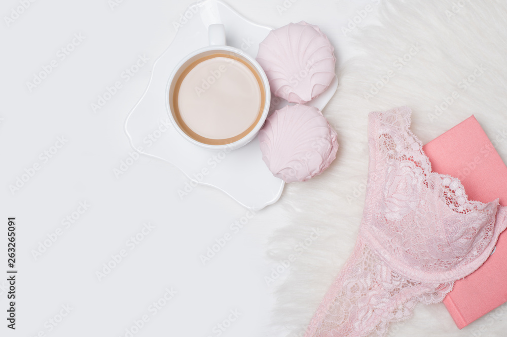 Cup of coffee with marshmallows. Pink lace bodice and notepad on white background. Fashionable concept. Cup of coffee with marshmallows. Pink lace bodice and notepad on white background. Fashionable concept.