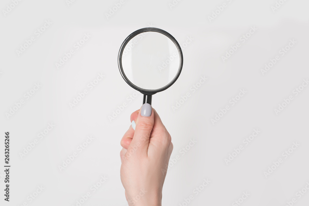 Female hand holding magnifier isolate on light background. Female hand holding magnifier isolate on light background.