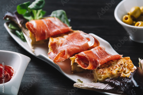 delicious Spanish potato omelette top with serrano ham, and olives