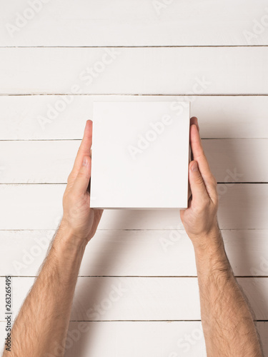 Small white cardboard boxes in male hands. Top view. White table on the background