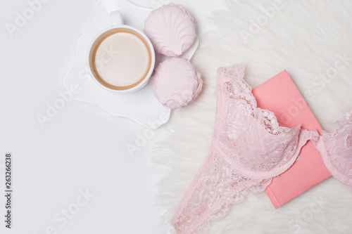 Cup of coffee with marshmallows. Pink lace bodice and notepad on white background. Fashionable concept.