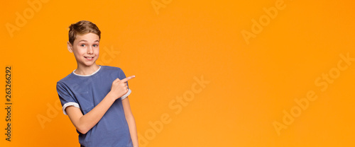 Emotional teen boy pointing aside at empty space
