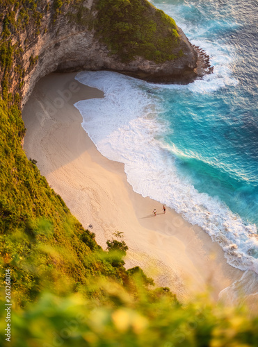 View of a people couple on the beach on Bali, Indonesia. Vacation and adventure. Beach and turquoise water. Top view from drone at beach, azure sea and relax couple. Travel and relax - image