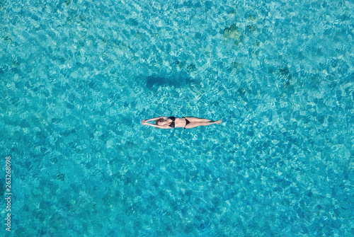 Aerial view of a girl on ocean on Bali, Indonesia. Vacation and adventure. Turquoise water. Top view from drone at ocean, azure watre and relax girl. Travel and relax - image