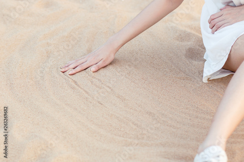 Tableau sur toile Girl sitting on the beach wipes the sand by hand