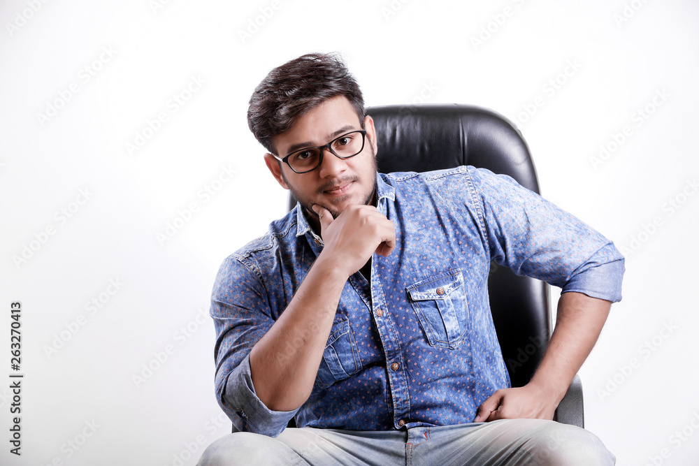 Handsome young Indian man siting on table isolated over white background Handsome young Indian man siting on table isolated over white background