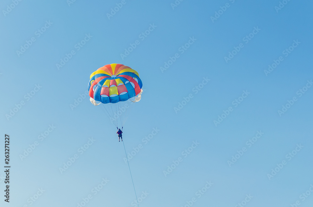 Parasailing is an extreme sport, people fly by parachute against the blue sky Parasailing is an extreme sport, people fly by parachute against the blue sky