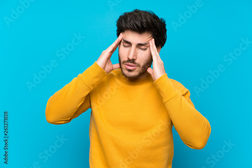 Handsome over isolated blue wall with headache