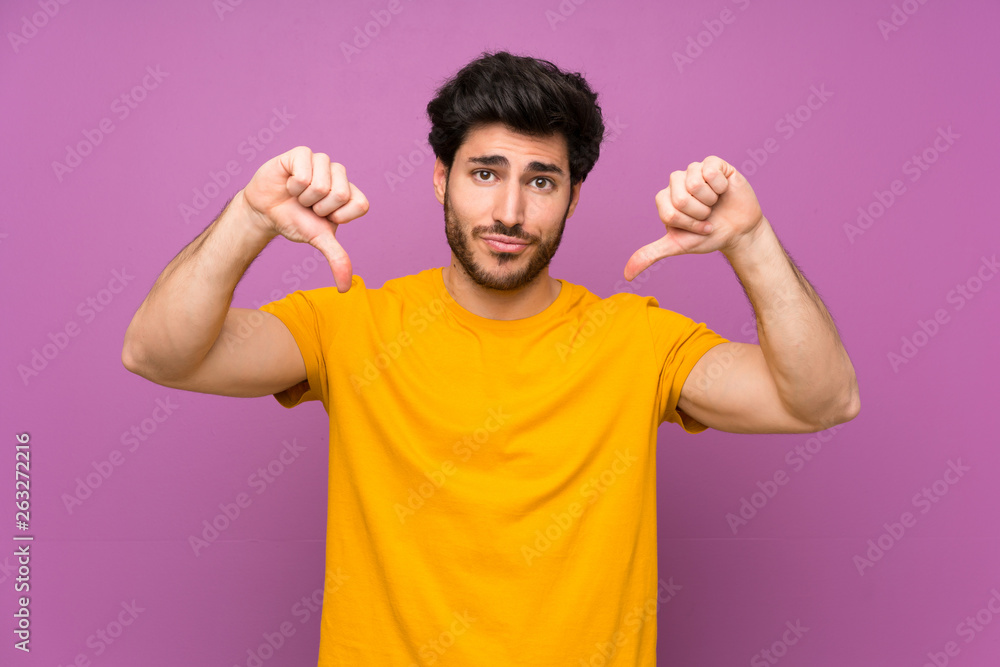 Handsome over isolated purple wall showing thumb down Handsome over isolated purple wall showing thumb down