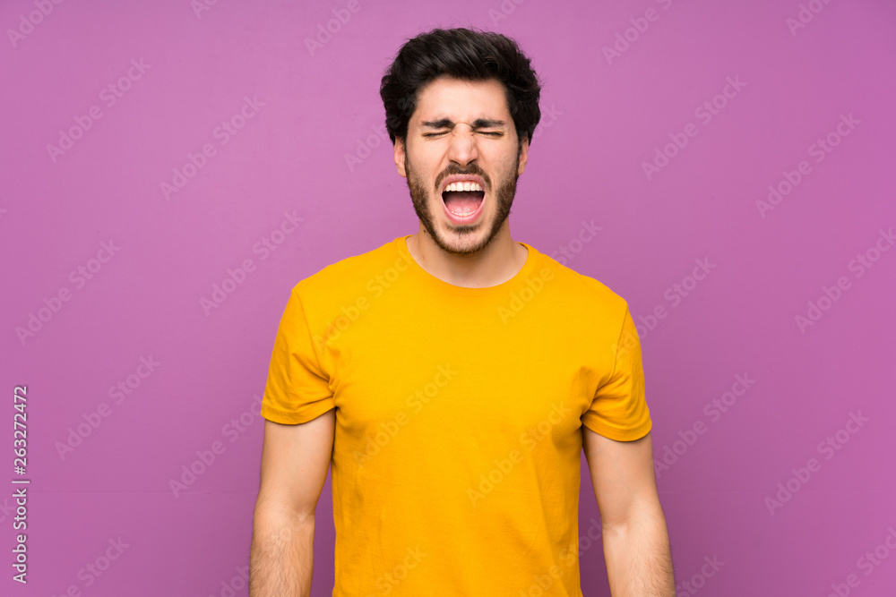 Fototapeta premium Handsome over isolated purple wall shouting to the front with mouth wide open