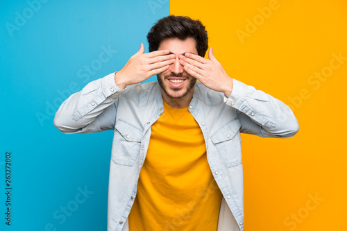 Handsome over isolated colorful background covering eyes by hands