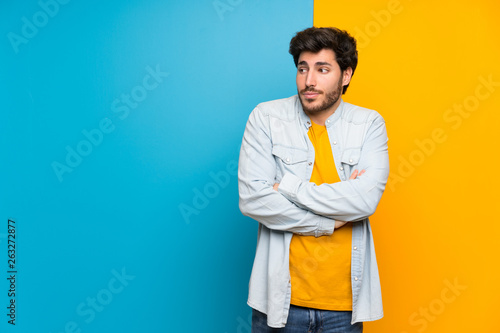 Handsome over isolated colorful background making doubts gesture while lifting the shoulders