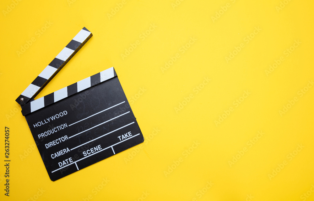 Movie clapperboard on yellow color background, top view