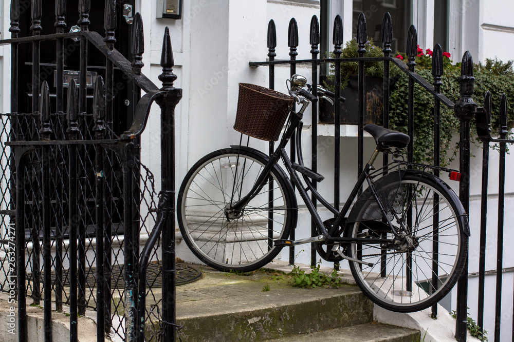 Vintage bicycle with basket on the porch. Entrance Door to residential building in London. Typical door in the English style