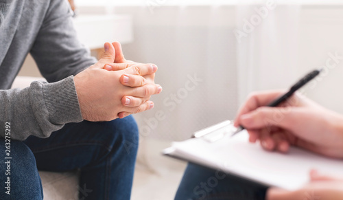 Therapist writing notes during counseling session with single man
