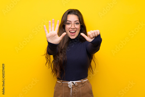 Teenager girl over isolated yellow wall counting six with fingers