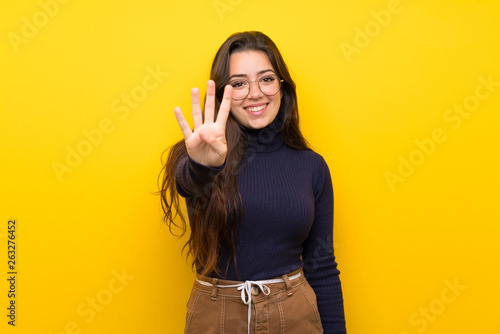 Teenager girl over isolated yellow wall happy and counting four with fingers